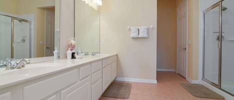 A bathroom with a large mirror, a double sink, and a glass shower enclosure.