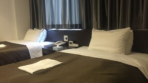 A hotel room with two beds, a bedside table with a phone and a small clock, and a window with curtains.