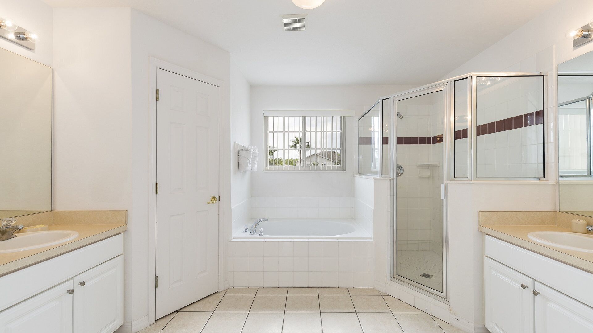 Een moderne badkamer met een badkuip, een douchecabine met glazen wanden en twee wastafels.