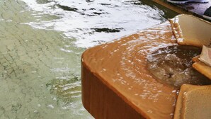 A bathtub with water running, a tiled floor, and a wooden edge. - Shiozawa Onsen Shichihokan (Takayama)