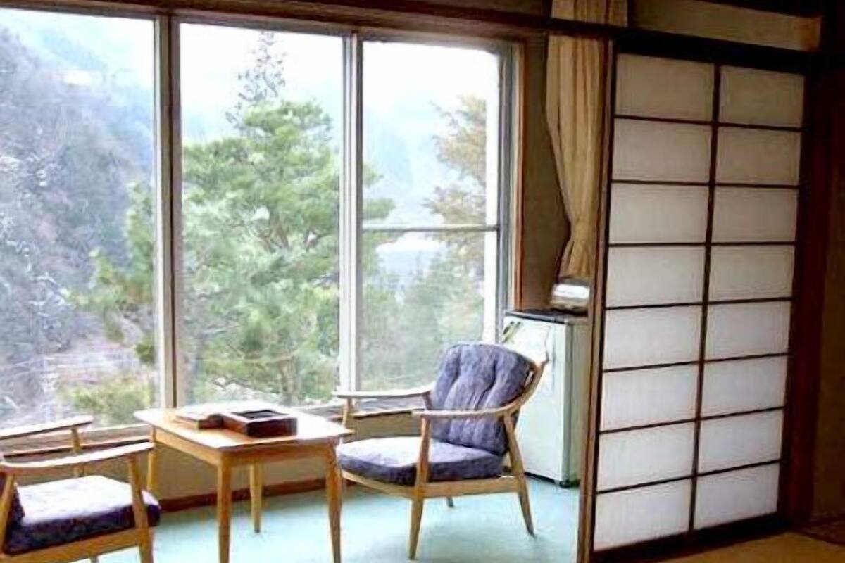 Una habitació amb combinació de tatami, taula baixa, cadira i llit futó.