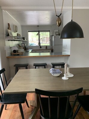A modern kitchen with a central island, black chairs, and a dining table. - NEXT TO GLAZE MEADOW, CUTE, WITH MANY AMENITIES! (Sisters)