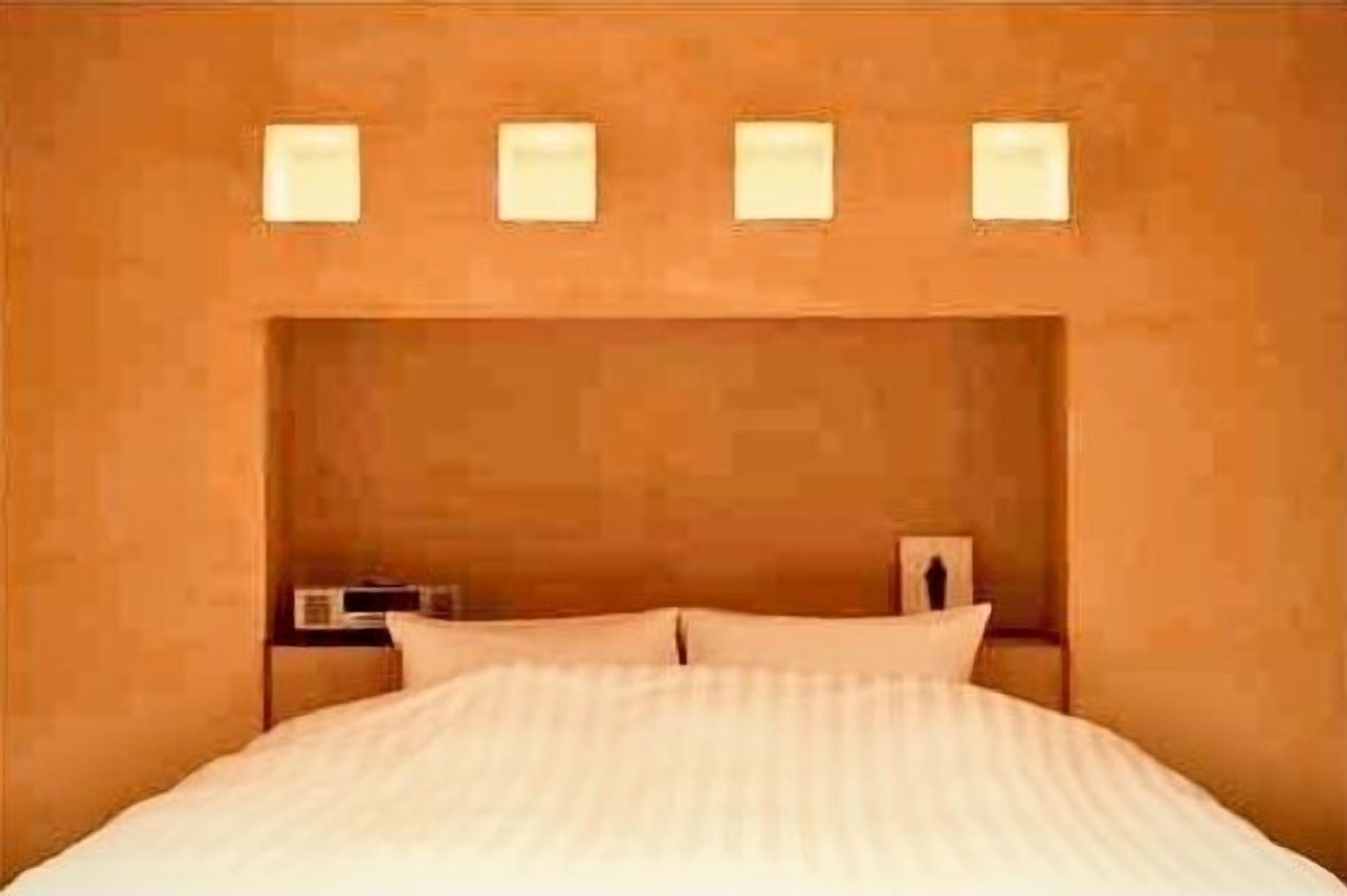 Un lit avec une tête de lit, une table de chevet avec une lampe et un luminaire fixé au mur.