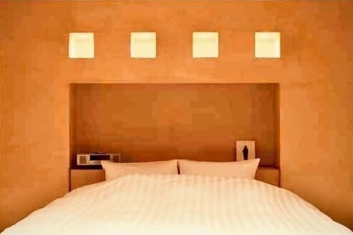 A bed with a headboard, a nightstand with a lamp, and a wall-mounted light fixture.