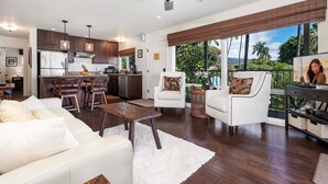 A modern kitchen with dark wood cabinets, stainless steel appliances, and pendant lighting. - 🏖️Oceanfront Kona Condo | Top Floor + Sunset Views (Kailua Kona)