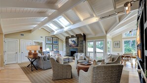A spacious living room with high ceilings, a fireplace, and large windows. - 12 Royal Tern - 2nd Row (70 yard walk) to the Ocean and Large Private Pool (Hilton Head Island)