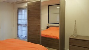A hotel room with a bed, a nightstand, a mirror, and a window with curtains.