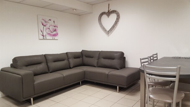 A modern living room with a sectional sofa, a dining table with chairs, and decorative wall art.
