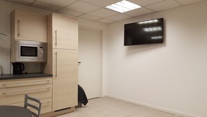 A kitchenette with a microwave, kettle, and cabinets.