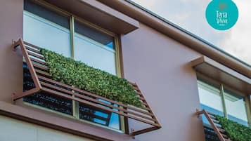 Un edificio moderno con balcones, plantas verdes y barandilla de metal.