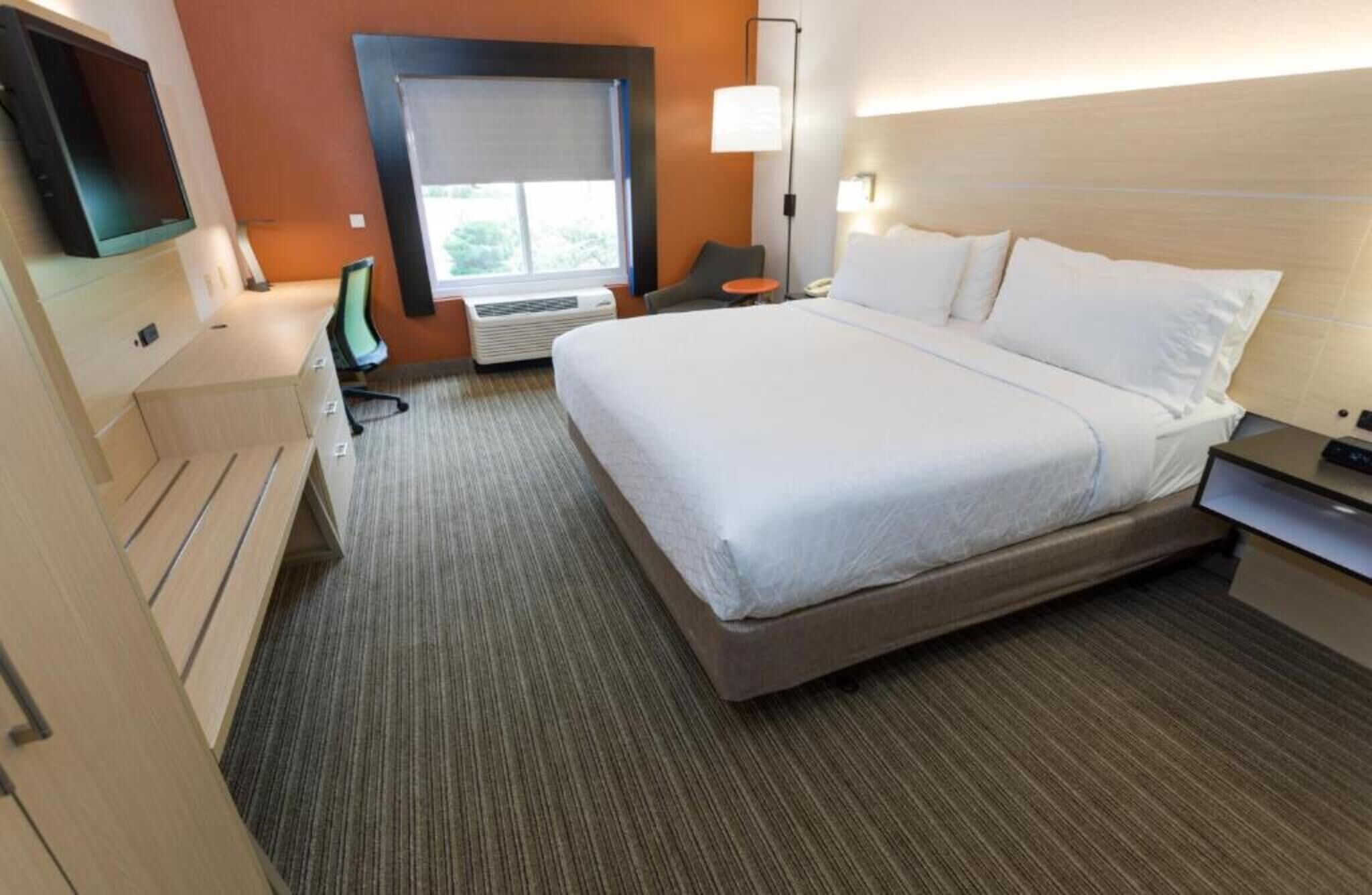 Una habitación de hotel con una cama, un escritorio, una silla, un televisor y una ventana.
