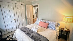Un dormitorio con cama, ventilador de techo, lámpara y puerta.