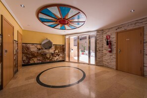 Eine Lobby mit kreisförmigem Boden, einem großen Kunstwerk an der Decke und einem Feuerlöscher an der Wand.