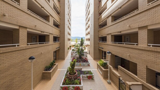 A multi-story building with a central courtyard featuring planters and a pathway.