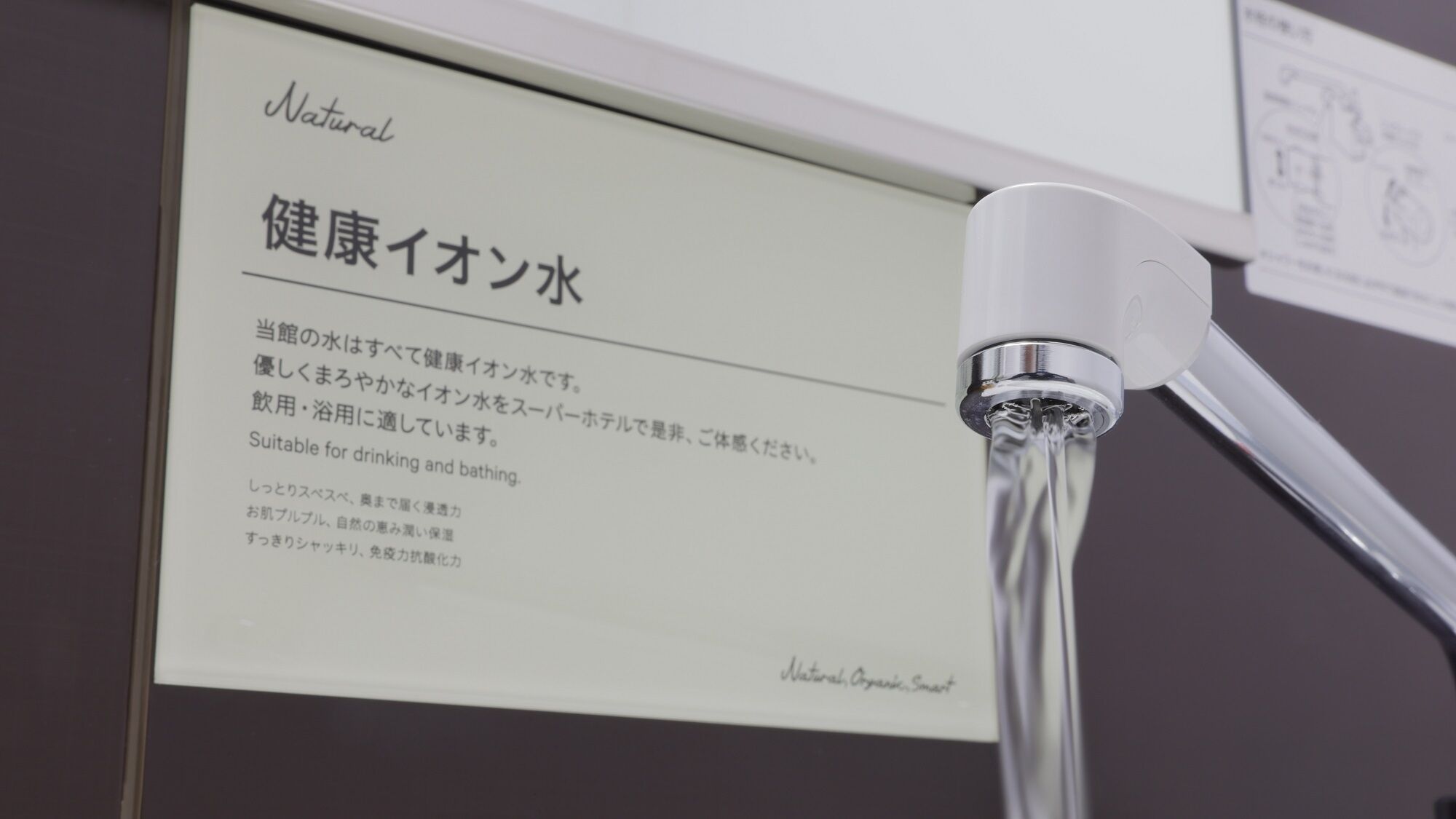 A sign with Japanese text and a faucet with water flowing.
