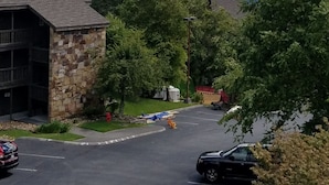 A parking lot with a stone building, trees, and mountains in the background.