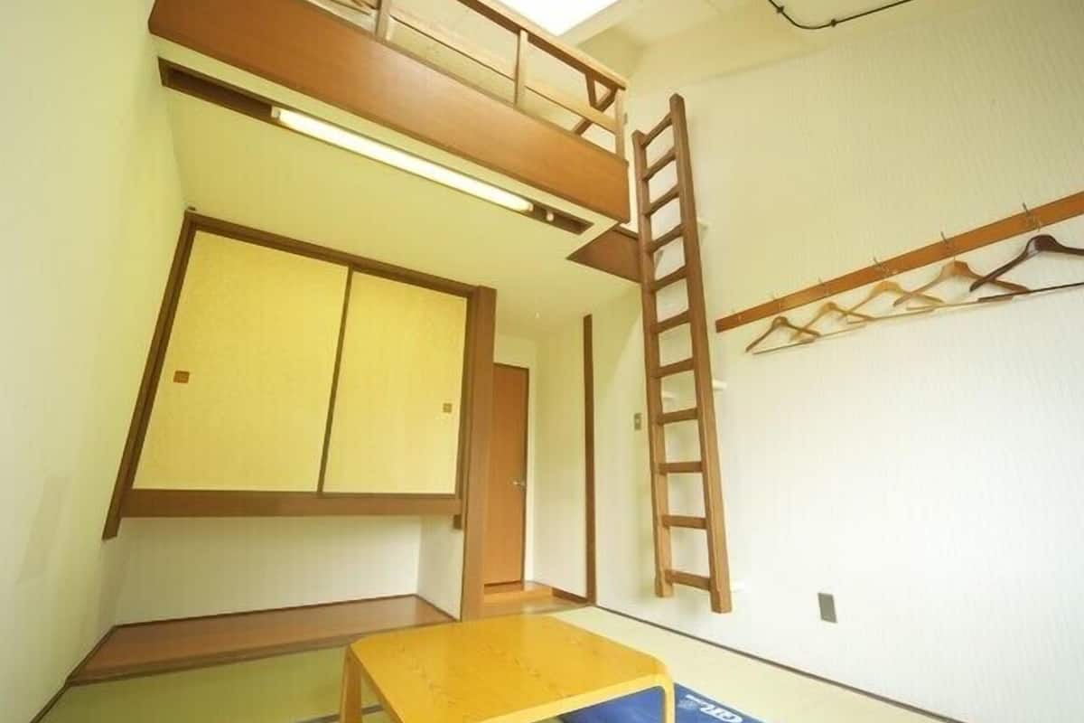 Una habitación con literas, una escalera, una mesa y un sofá cama.