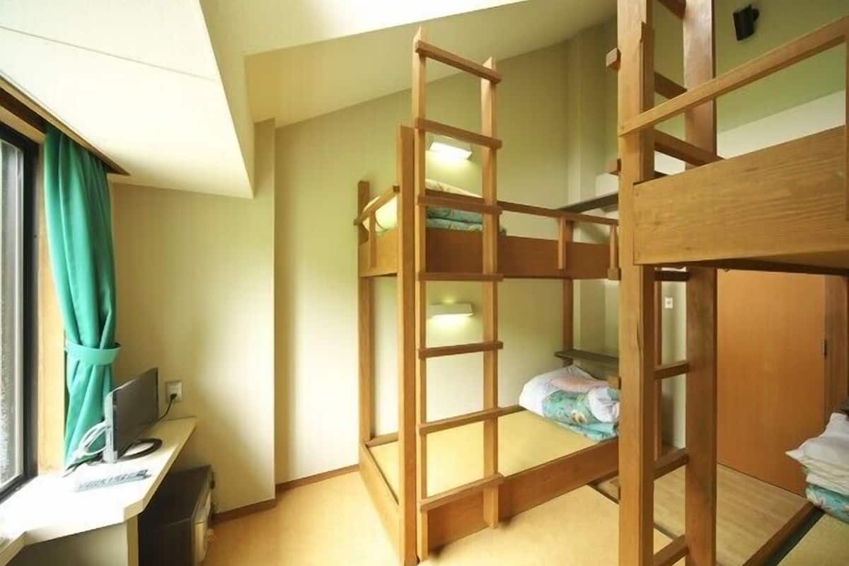 Habitación con literas, un escritorio y una computadora.