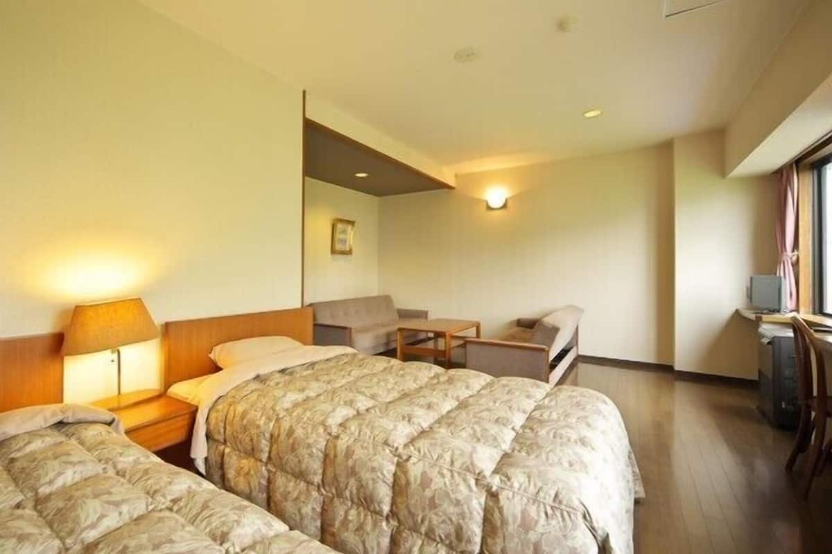 Una habitación de hotel con dos camas, un escritorio, una silla y una lámpara.