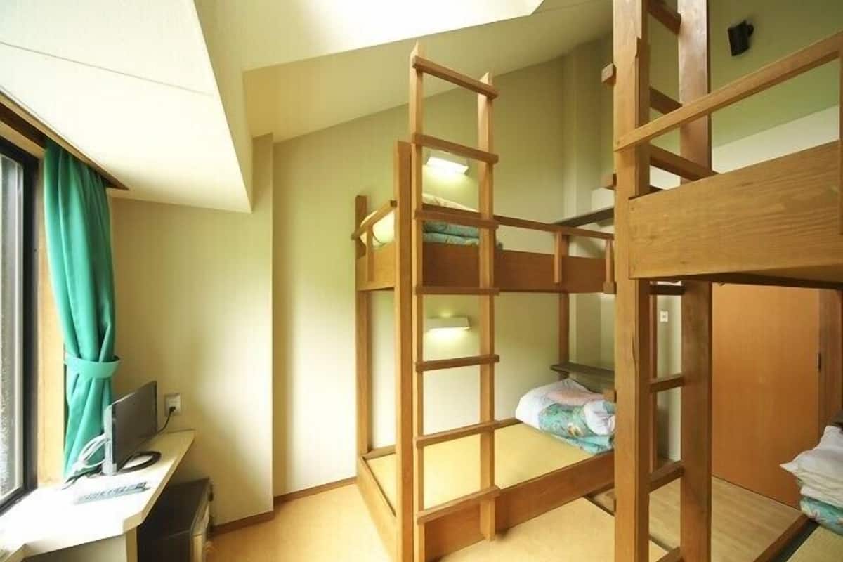 Habitación con literas, un escritorio y una computadora.