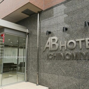 Ein Hotel Eingang mit Glastür und einem Schild, auf dem 'ABHOTEL CHINOMIYA' steht.