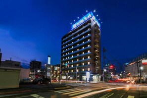 Un hotel de varios pisos con un letrero llamativo en la parte superior y un estacionamiento en primer plano.