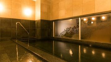 Una piscina con pared de vidrio, barandilla metálica y suelo de baldosas.