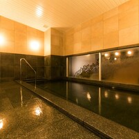 Una piscina con pared de vidrio, barandilla metálica y suelo de baldosas.