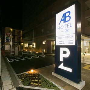 Señal de hotel que muestra 'AB HOTEL' y una señal de estacionamiento con la letra 'P' indicando una zona de estacionamiento.