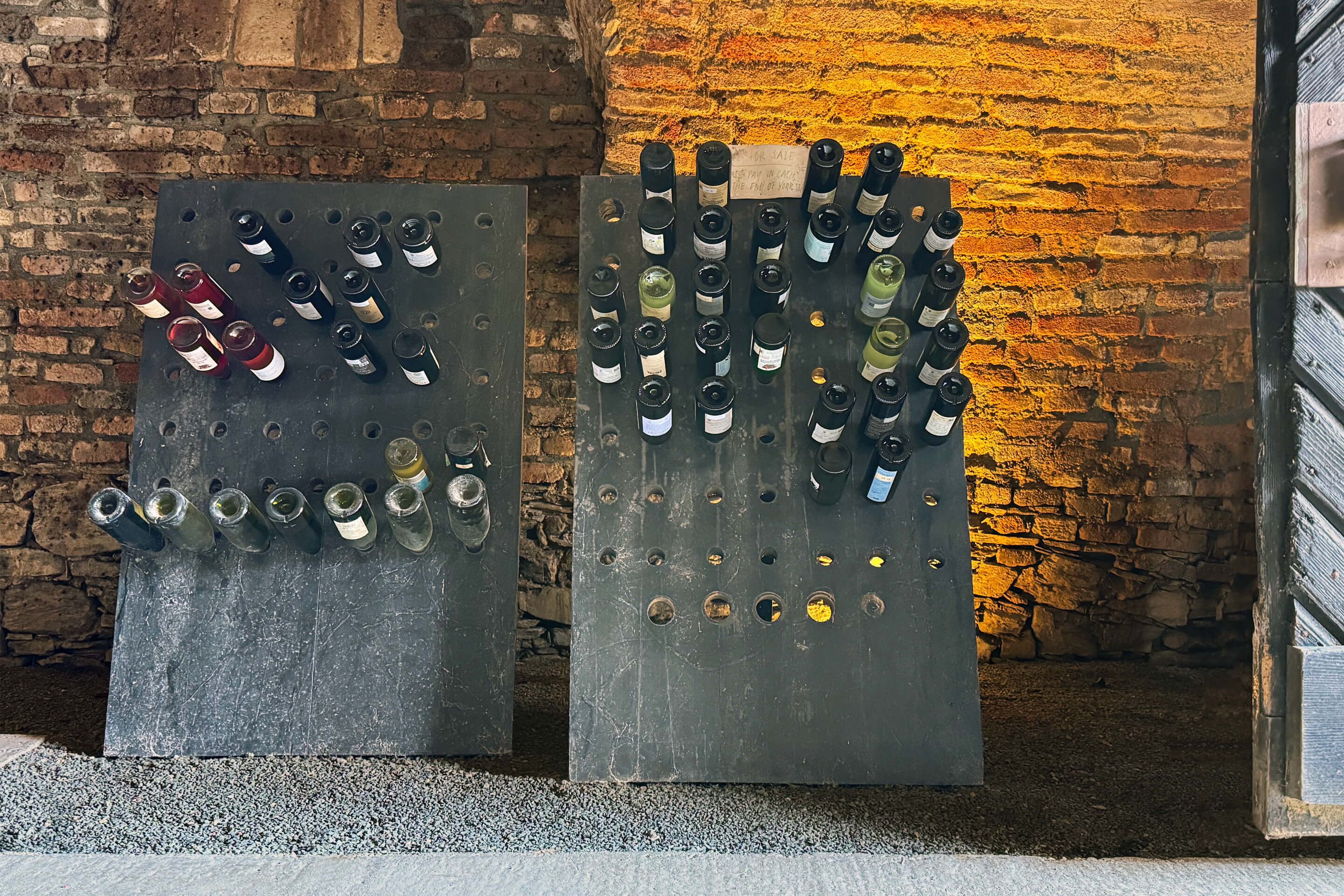 Two metal boards with bottles against a brick wall.