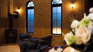 A room with brick walls, two arched windows, a fireplace, and a table with a vase of flowers.