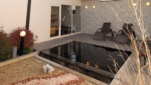 A modern house with a swimming pool, a covered patio, and a glass door leading to a garage.