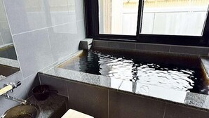 A bathroom with a bathtub, a sink, and a wooden stool.