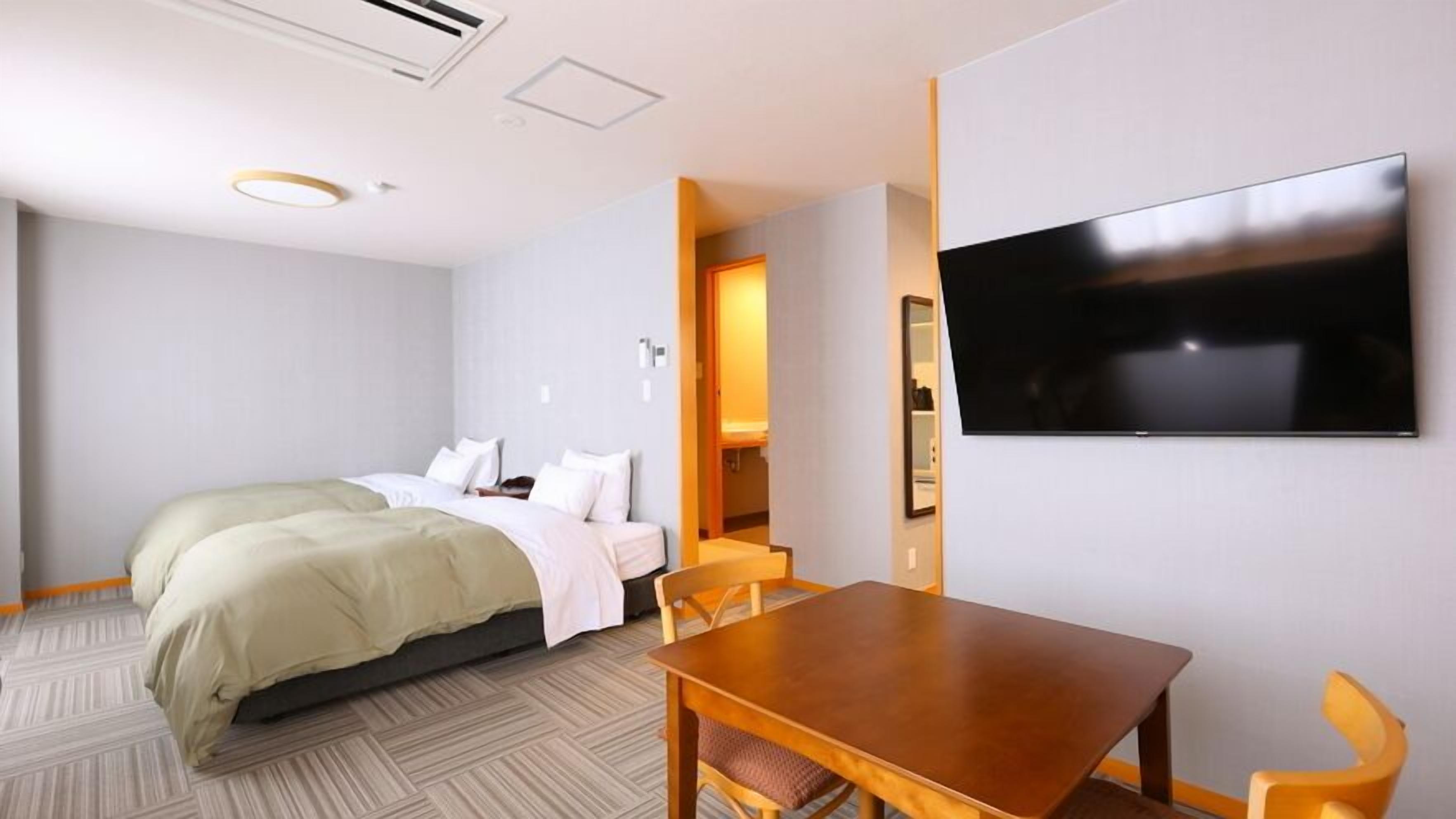 Une chambre d’hôtel avec un lit, une télévision, une table à manger et des chaises.
