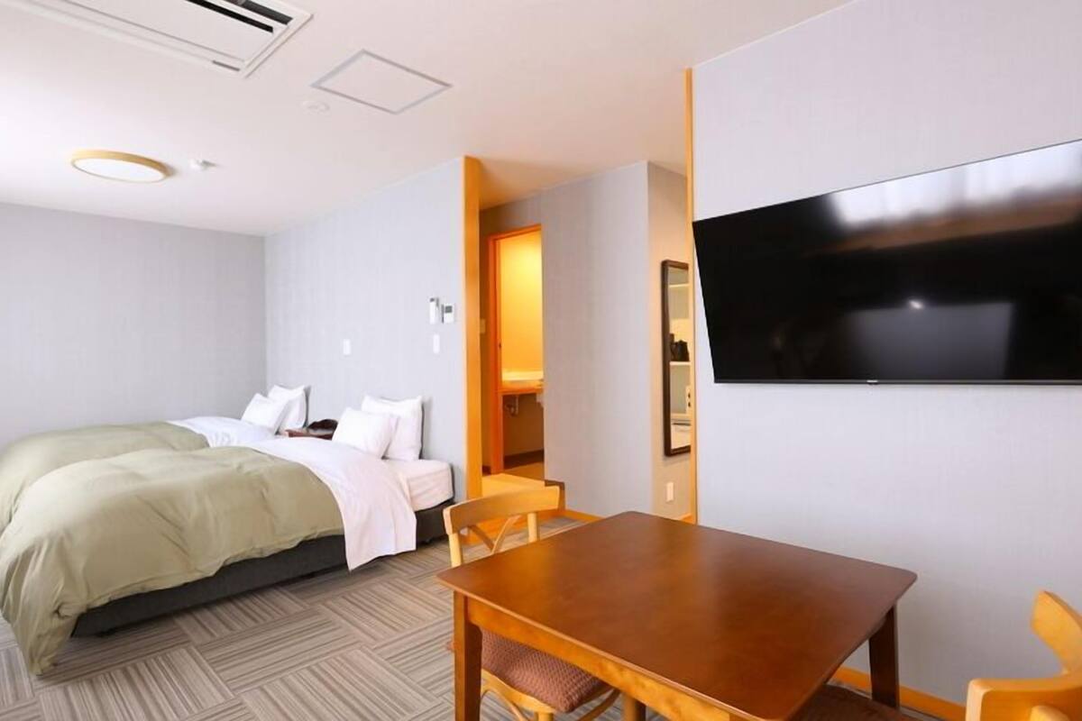 Une chambre d’hôtel avec un lit, une télévision, une table à manger et des chaises.