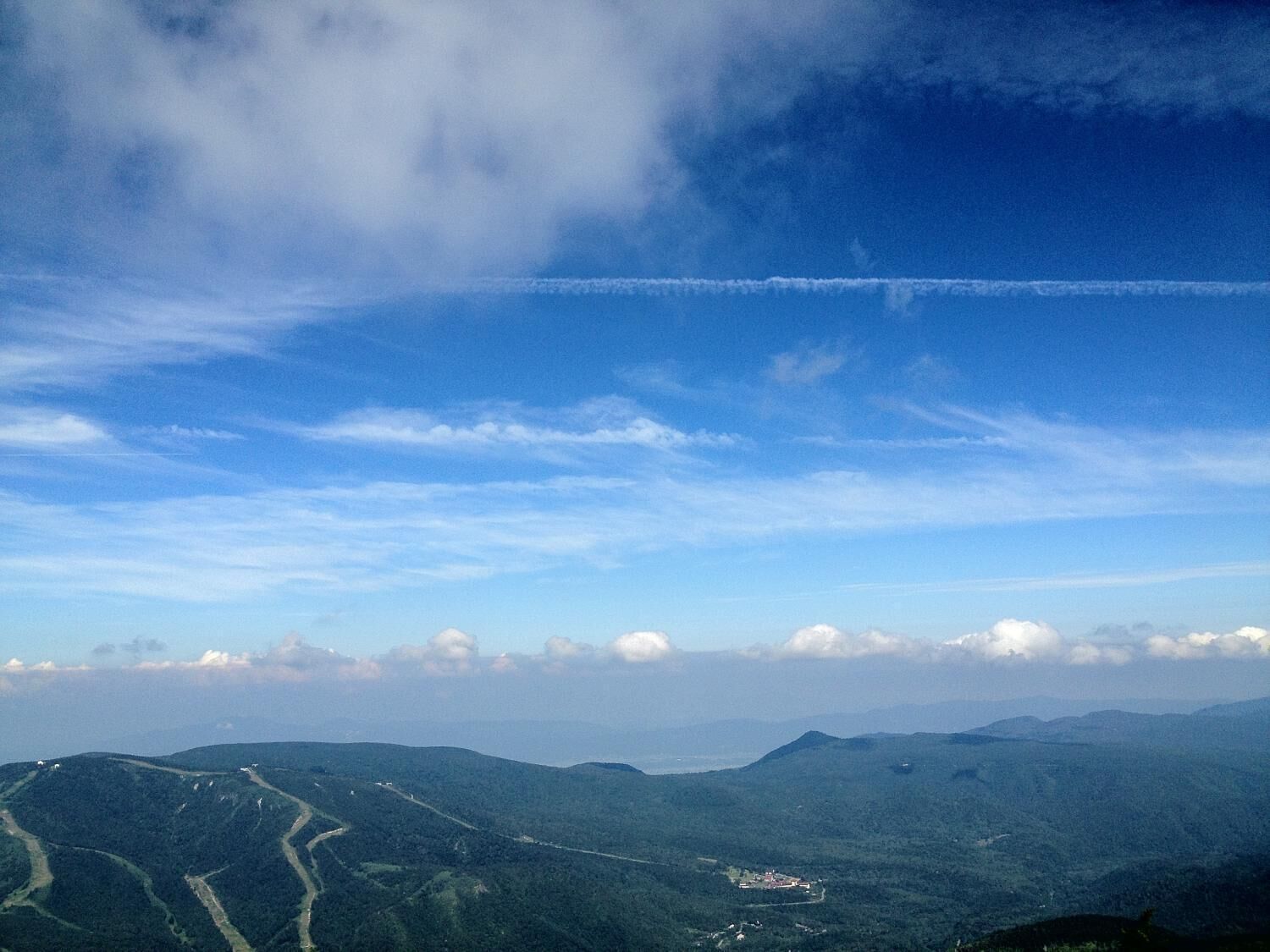 Et bjerglandskab med klar himmel og et tydeligt spor efter et fly.