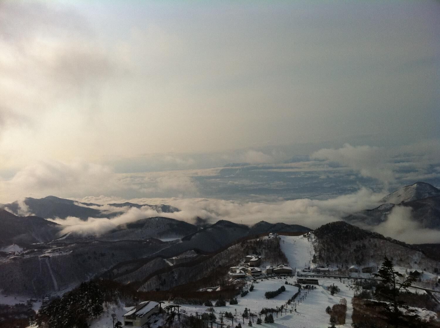 A mountainous landscape with a ski resort, including buildings and ski lifts.