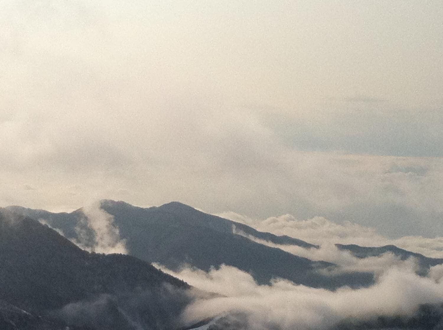 A mountainous landscape with clouds at the base of the peaks.