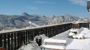 Een sneeuwbedekte balkon met uitzicht op bergen.