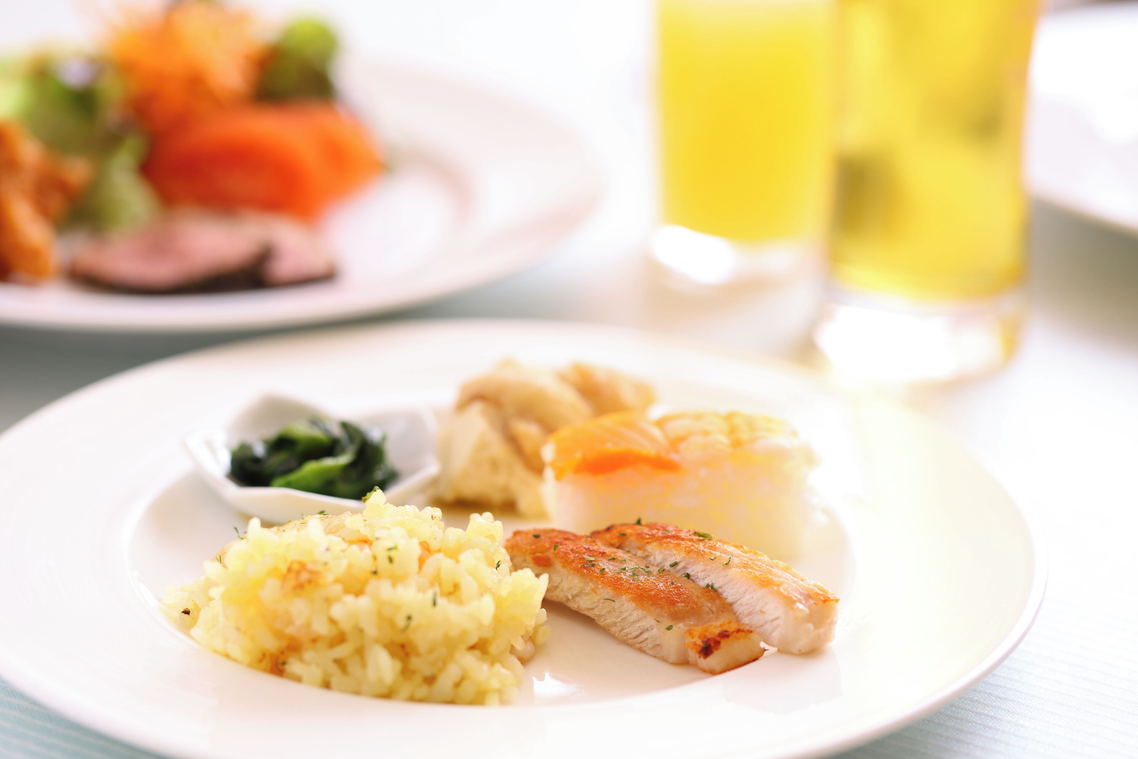 A plate with a piece of fish, mashed potatoes, and a small bowl of greens.
