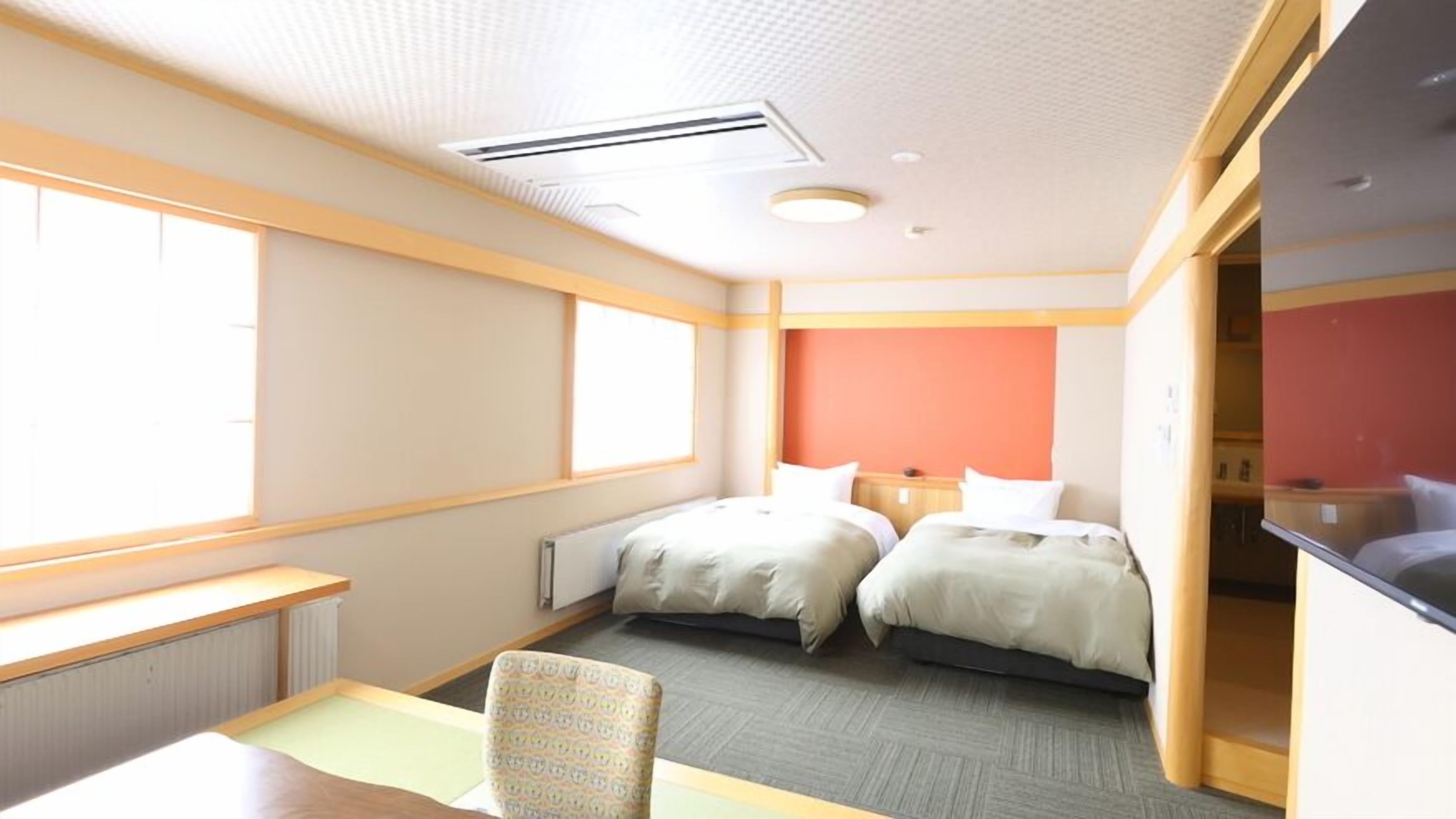 Une chambre d’hôtel avec deux lits, un bureau, une chaise et une fenêtre.
