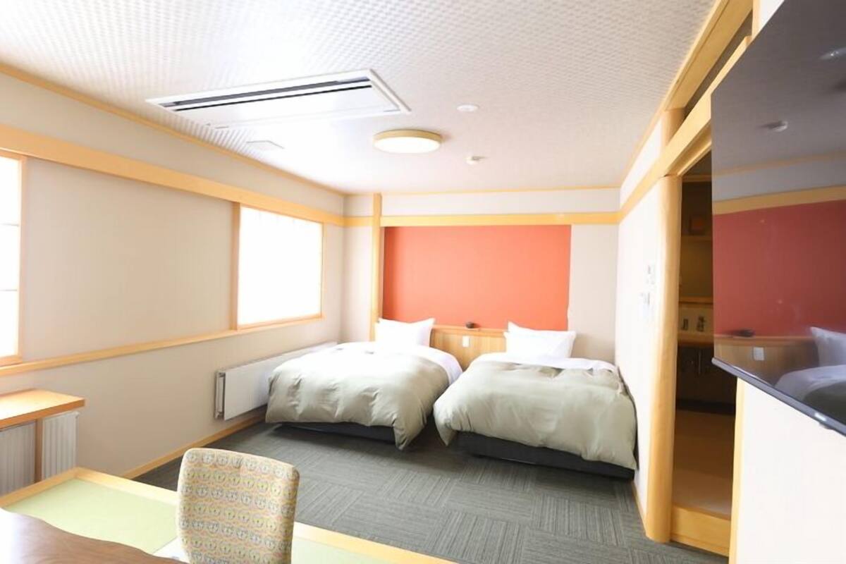 Une chambre d’hôtel avec deux lits, un bureau, une chaise et une fenêtre.
