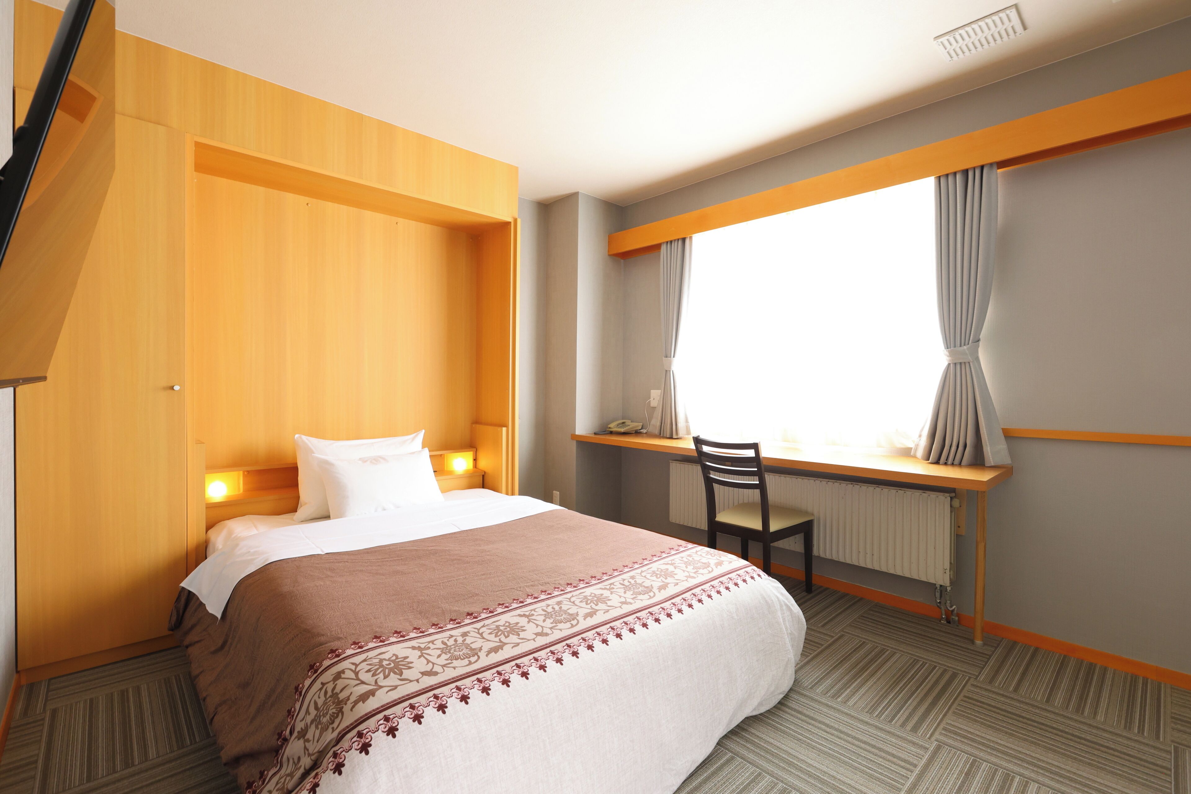 A hotel room with a bed, a desk, and a chair.