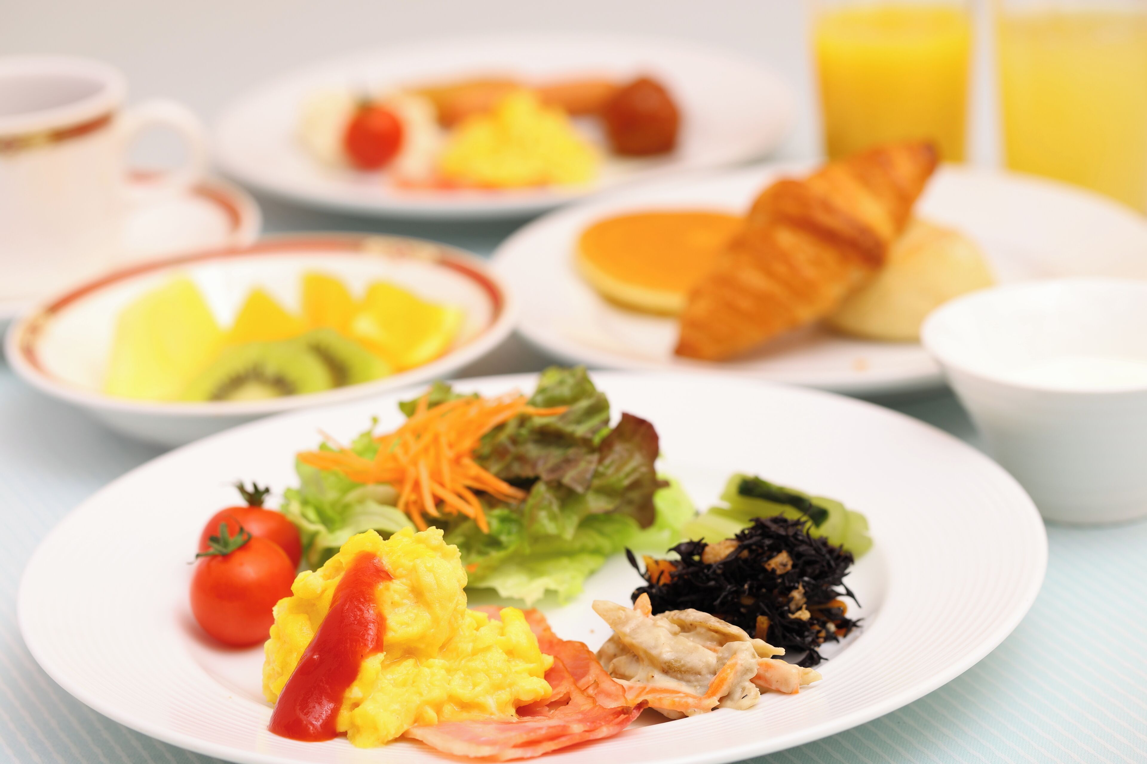 A breakfast setting with plates of eggs, toast, and fruit.