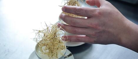 A hand holding a cup with a white substance and dried plant material.
