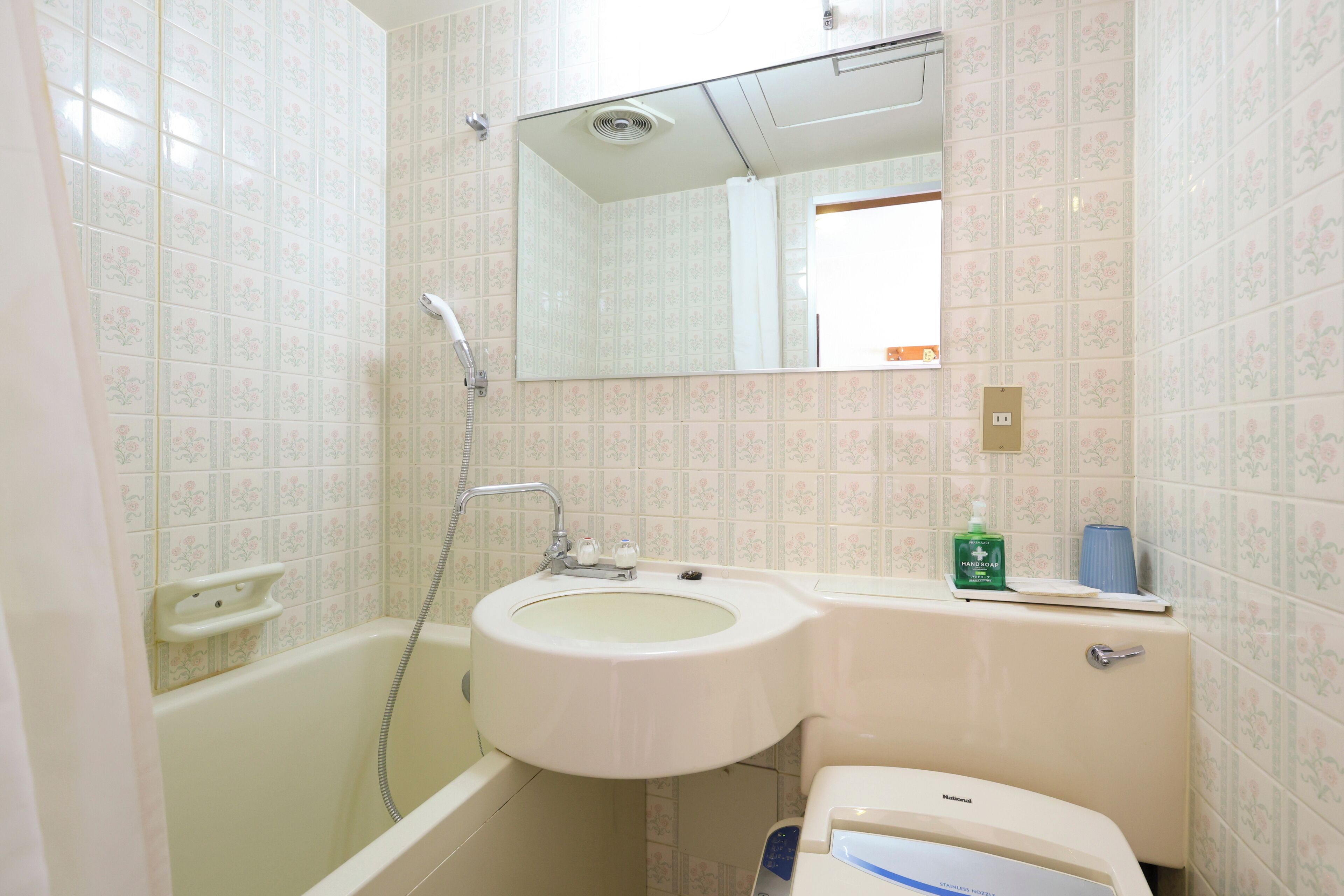 A bathroom with a bathtub, sink, and toilet, featuring floral patterned tiles and a mirror above the sink.