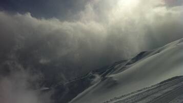 Montaña nevada con cielo despejado y rayos de sol filtrándose entre las nubes.