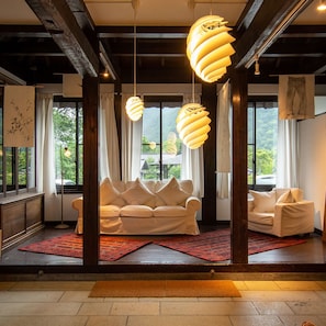 A modern living room with a sofa, two hanging lamps, and large windows.