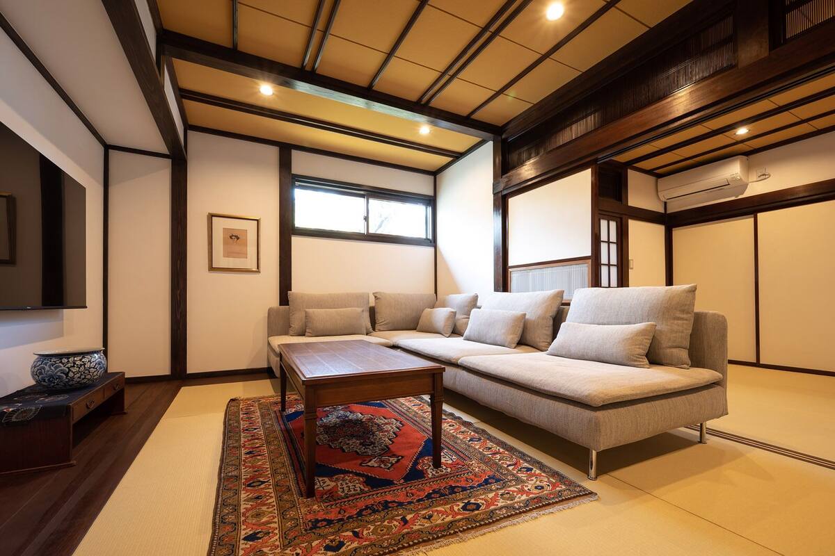 A modern living room with a sofa, coffee table, and traditional rug.