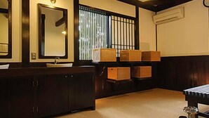 Habitació japonesa tradicional amb sostre de fusta, un mirall gran, un lavabo i caixes d'emmagatzematge.